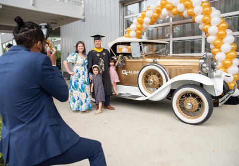 Graduate and family posing with the The Ramblin’ Reck.