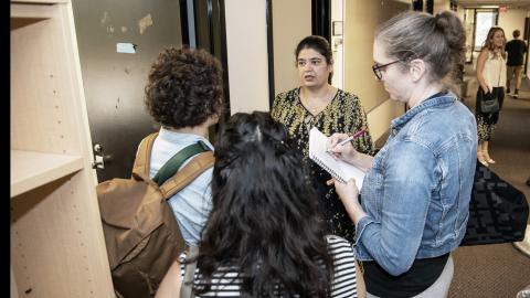 A group of people stand in a hallway having a conversation