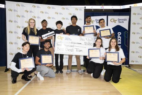 Both winning teams from the Fall 2023 Capstone Design Expo pose with their certificates and oversized check.