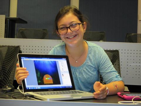 Student smiling and displaying STEM work on a laptop