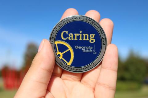 Front image of caring coin with gear and text Caring