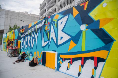 Artists painting the mural on the wall that surrounds the Georgia Tech microgrid facility.