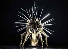 Dancers of MOMIX hold light rods that are fanned out create a radiating circle of light.