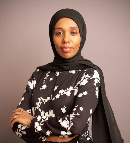Woman in hijab standing with her arms folded in front of her