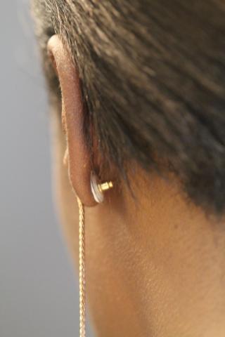 Contraceptive earring on a woman's ear - vertical format