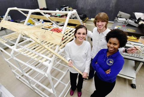 Mechanical engineering major Taylor Benson and aerospace engineering major Brett Rushing pose with Dr. Joy Harris in front of the Smart Water drying tent framework.