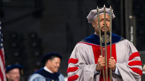 Charles Isbell, senior associate dean and professor in the College of Computing, carries the mace at Commencement