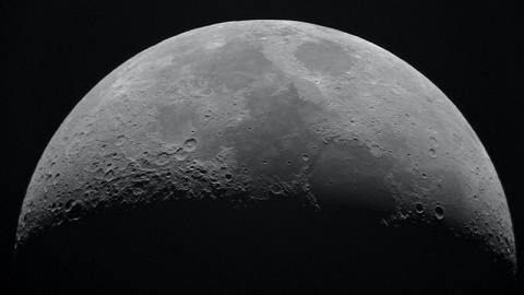 the top two thirds of the moon, illuminated by the sun, against pitch black space