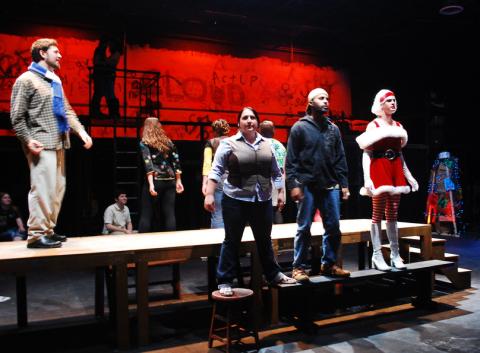 Students in various costumes grouped on risers with dramatic red light in background