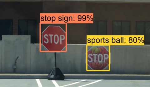 Image of a real stop sign with a bounding box and a fake stop sign with a bounding box and incorrect label saying 'sports ball'