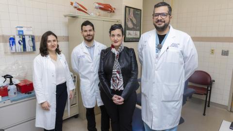 School of Interactive Computing Associate Professor Rosa Arriaga, in a black leather jacker, poses for photo with three researcher collaborators each wearing white lab coats.