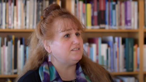 Margaret E. Kosal talking against a blurred backdrop of bookshelves.