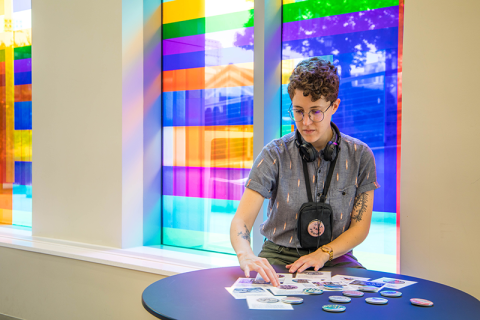 A student sorts buttons against a colorful rainbow backdrop