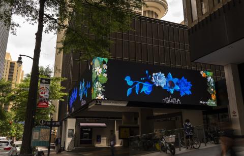 a billboard marquee on the front of a building shows animated flowers and foliage