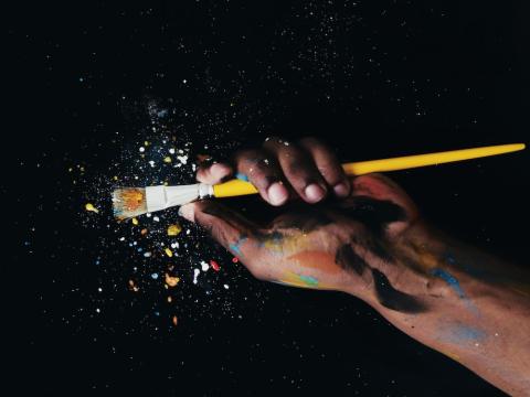 The image shows a picture of a hand with a paint brush and paint splatter.