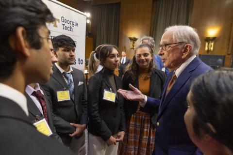 A group of people in business attire, including former U.S. Sen. Sam Nunn, speaking