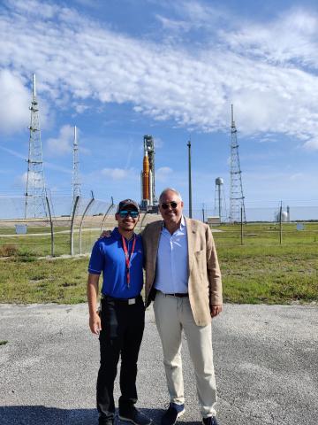 Corey Crisostomo stands with Ángel Cabrera, president of Georgia Tech, in front of an Artemis rocket.