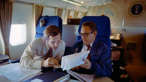 Two men sitting on Air Force One looking at documents.