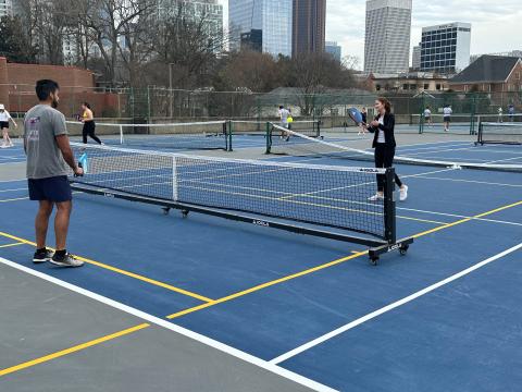 A male student and a female student play pickleball on the Peters Parking Deck courts