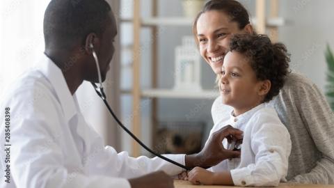 A pediatrician listens to a young patient's heartbeat with a stethoscope
