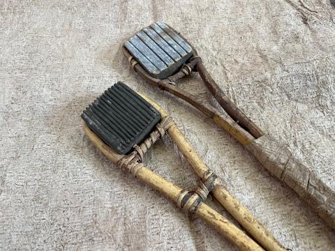 two grooved, square stones with wooden handles on top of beige paper-like material