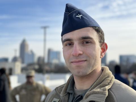 An ROTC cadet in uniform stands in front of the Atlanta skyline on the Georgia Tech campus
