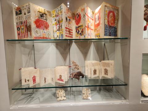 Accordion-folded paper objects in display case
