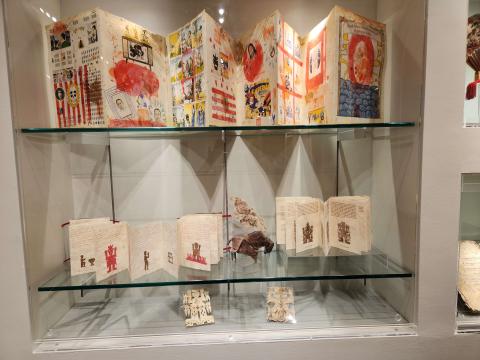 Accordion-folded paper objects in display case