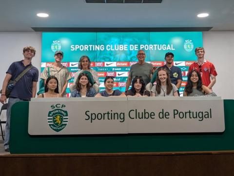 Group photo at table with Sporting Clube de Portugal banner.