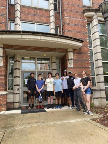 Students stand in front of a brick dormitory.