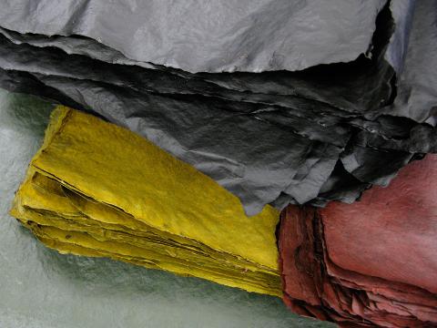 stack of black paper on top of stack of yellow paper and stack or red paper