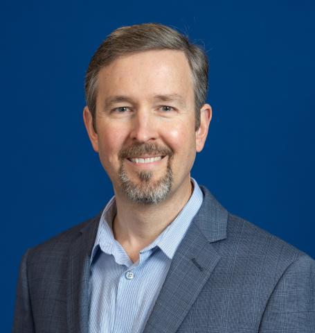 Brian Umberger Headshot with grey suit and blue collared shirt