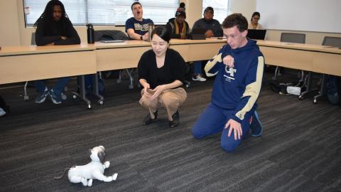 A robot dog sits in front of Assistant Professor Jennifer Kim and a student from the Georgia Tech Excel program.