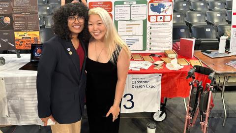 Two college students stand in front of a table with academic posters and a sign that reads "Georgia Tech Capstone Expo."