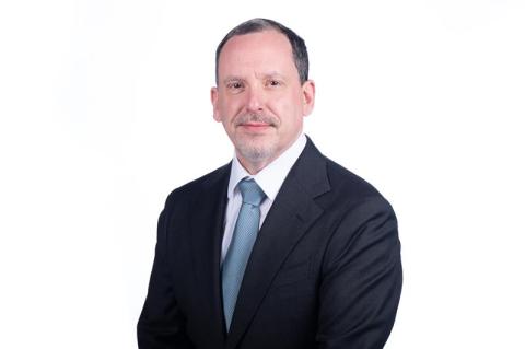 Headshot of Didier Contis in navy blue suit, with white shirt and blue tie.
