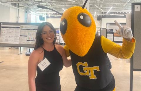 A young woman stands with the Georgia Tech mascot Buzz