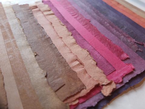 spread stack of handmade papers in shades of browns, prinks, purples, and oranges