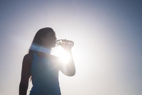 Woman drinks water under summer sun.