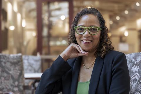 woman sitting with her hand on her chin, wearing a green shirt and green glasses