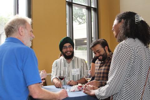 Four alumni talk around a table.
