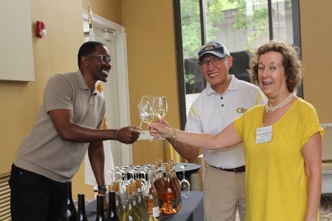 Three people raise their glasses in a toast.