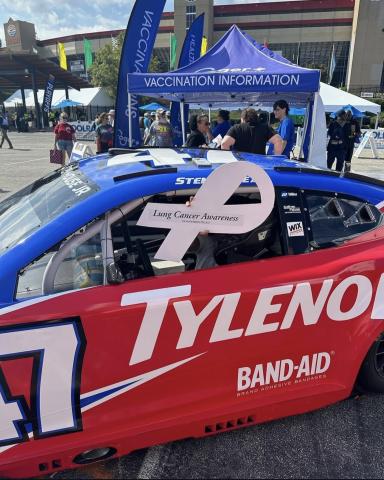 Red race car sporting a white ribbon for lung cancer awareness