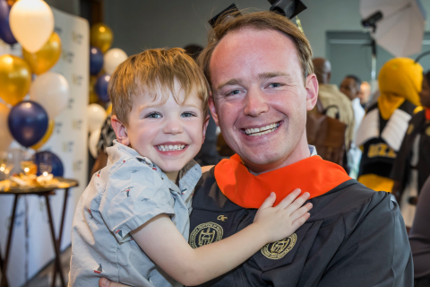 Photo of a recent graduate and a young child celebrating commencement.