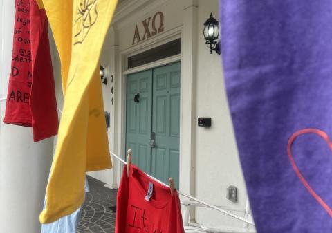 Decorated shirts are displayed in front of the Alpha Chi Omega sorority house