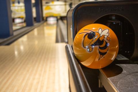 A yellow bowling ball with Buzz on it sits in front of a bowling lane