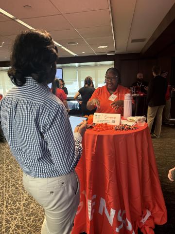 A woman speaks with a student at a round table.