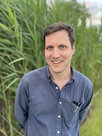 Man standing in front of grassy area in nature.