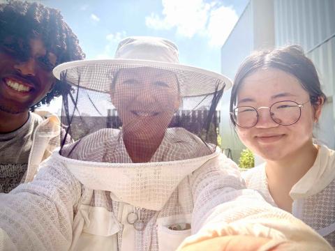 Two women and one man including woman in bee-keeping hat