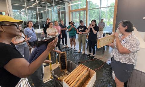 Woman teaching a class and holding a honeycomb.