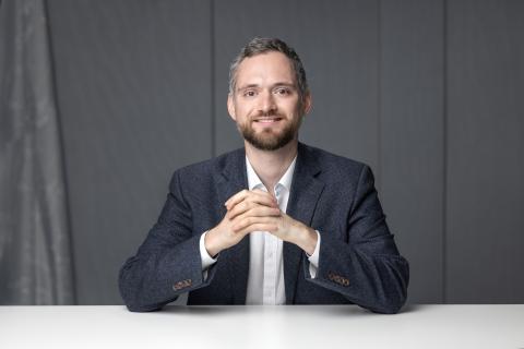 Joseph Greene, seated with hands clasped.
